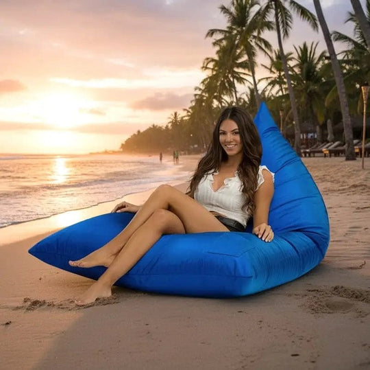Woman sitting on a blue bean bag chair on a beach at sunset