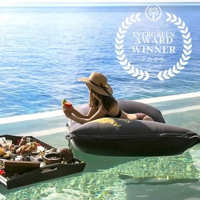 Woman relaxing on an inflatable lounger by a pool with a 'Green Award Winner' badge overlay.