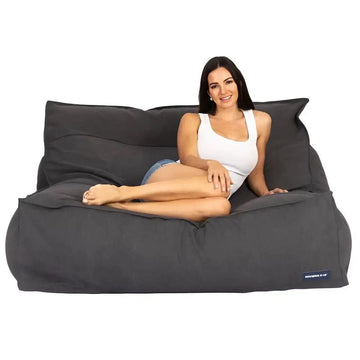 Woman sitting on a large black bean bag chair against a white background