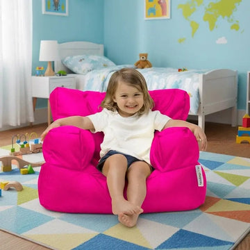 Child sitting on a bright pink bean bag chair in a colorful bedroom.
