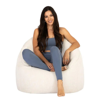 Woman sitting on a white bean bag chair against a white background