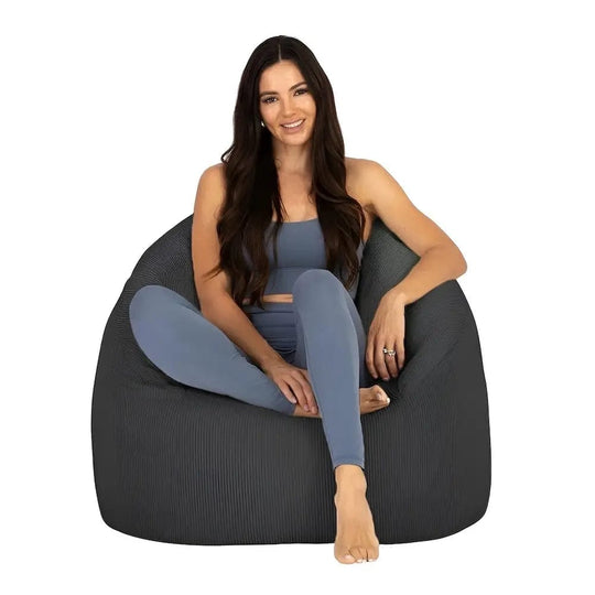 Woman sitting on a dark gray bean bag chair against a white background