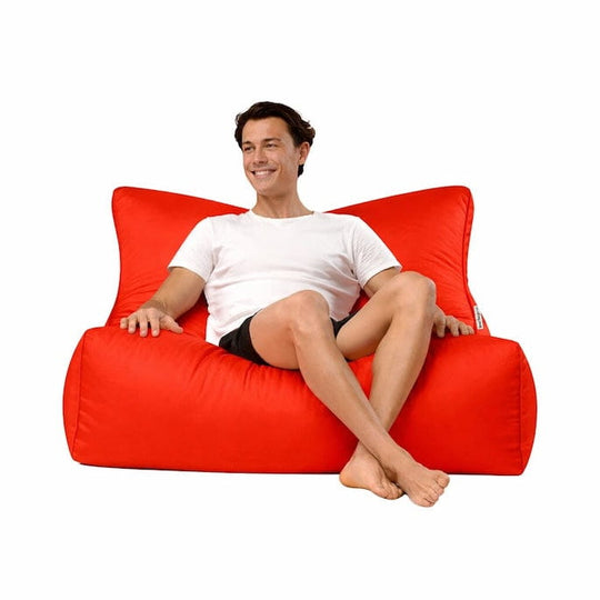 man sitting on a bright red bean bag lounger