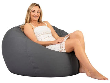 Woman sitting on a gray bean bag chair against a white background