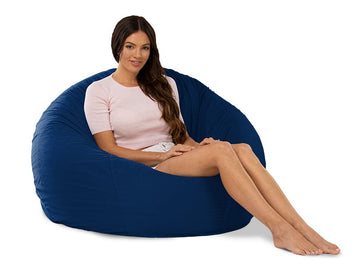 Woman sitting on a large navy bean bag chair against a white background
