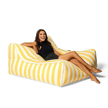 Woman sitting on a yellow and white striped bean bag chair against a white background