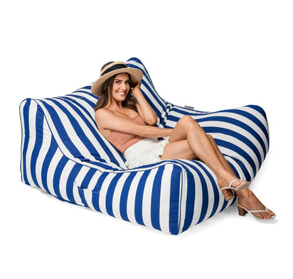Woman sitting on a blue and white striped bean bag chair against a white background