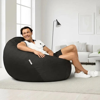 Person sitting on a black bean bag chair in a modern living room.