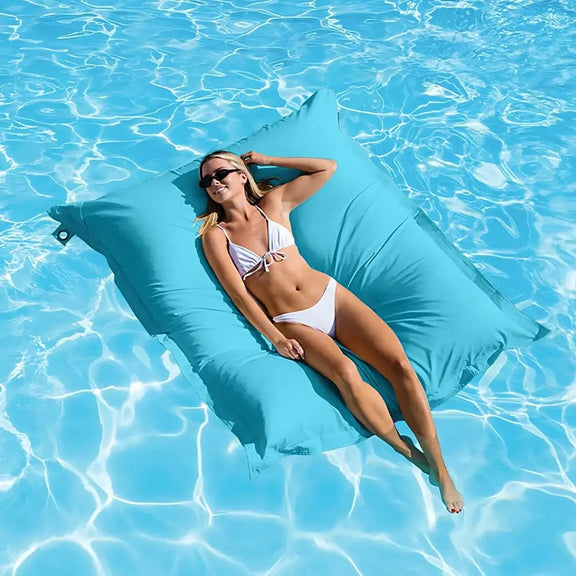 Woman lounging on a blue pool float in clear blue water