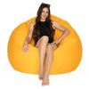 Woman sitting on a large orange bean bag chair against a white background