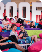 People sitting on colorful bean bags in a modern indoor setting with large letters in the background